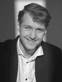 Portraitfoto von Marc Verhaelen in Hemd und Sakko, freundlich lächelnd, schwarz-weiß aufgenommen mit Licht und Schatten im Gesicht