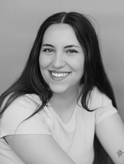 Lächelndes Porträt von Magdalena Echter mit langen Haaren, sitzend, mit tätowiertem Arm sichtbar, Schwarz-Weiß-Foto