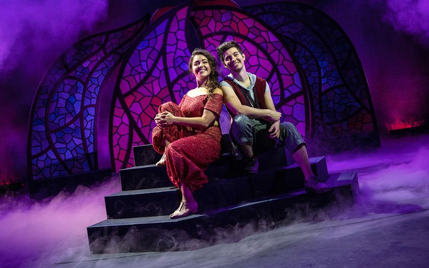 Aladin und Prinzessin Yasmin sitzen eng beieinander auf einer Treppe vor einem orientalischen Bühnenbild.