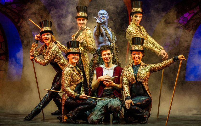 Dschinni, umringt von Tänzerinnen mit Zylindern, steht hinter Aladin, der die Wunderlampe hält.