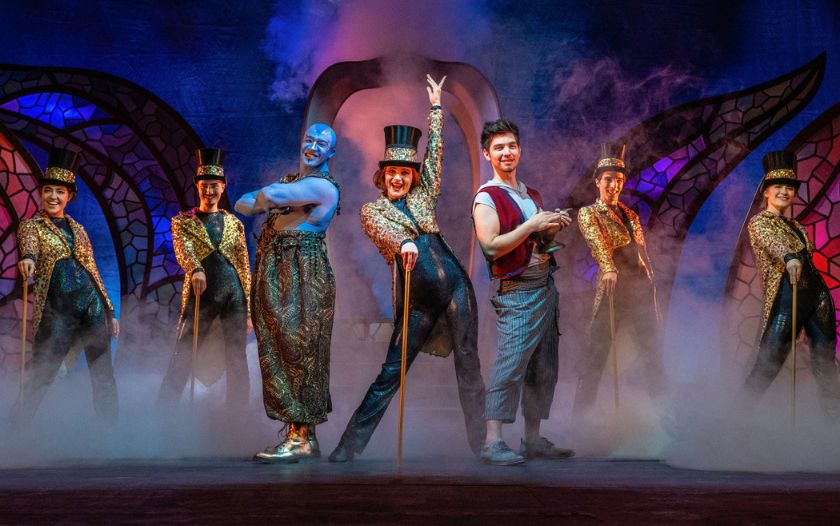 Aladin und der Dschinni tanzen gemeinsam mit vier weiteren Tänzerinnen in glitzernden Kostümen auf der Bühne.