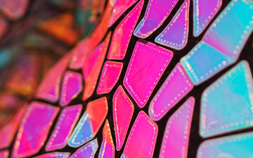 Nahaufnahme von bunten, irisierenden Flächen der Kostüme mit geometrischem Muster.