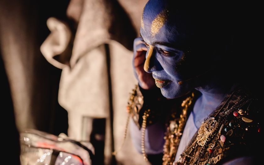 Der Darsteller des Dschinni bereitet sich im Kostüm und mit goldener Schminke im Gesicht auf seinen Auftritt vor.