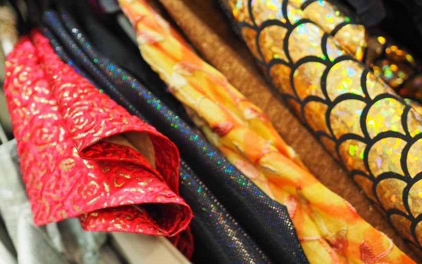 Unterschiedliche Stoffe in kräftigen Farben und Mustern hängen ordentlich nebeneinander.