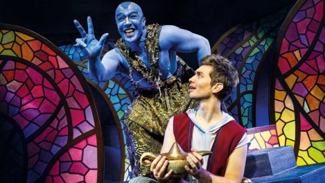 Dschinni erscheint aus der Lampe und begrüßt Aladin, der diese Lampe in der Hand hält, mit breitem Grinsen.