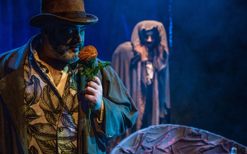 Belles Vater mit Rose in der Hand, im Hintergrund erscheint das Biest in einem dunklen Wald