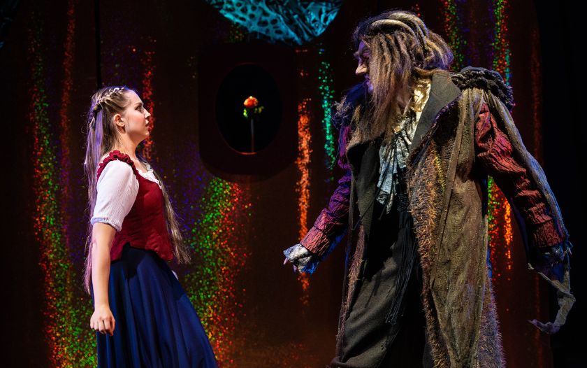 Belle und Biest stehen sich im Schloss gegenüber, im Hintergrund die Rose