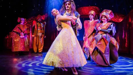 Belle und Biest tanzen in festlicher Atmosphäre umgeben von Schlossbewohnern