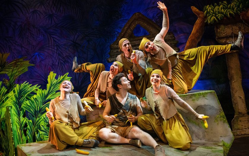 Mogli sitzt mit einer Affenbande lachend auf einer Dschungel-Ruine