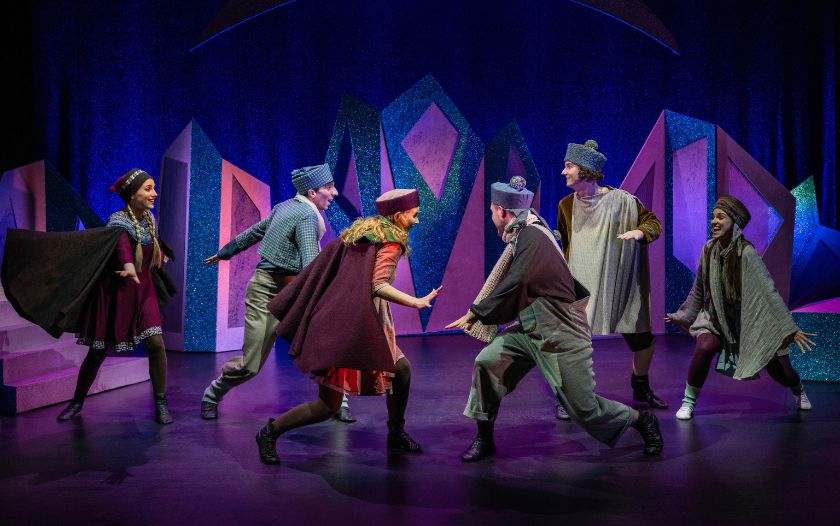 Fröhliche Kinder in warmer Winterkleidung tanzen auf der Bühne im Musical Schneekönigin - das Musical