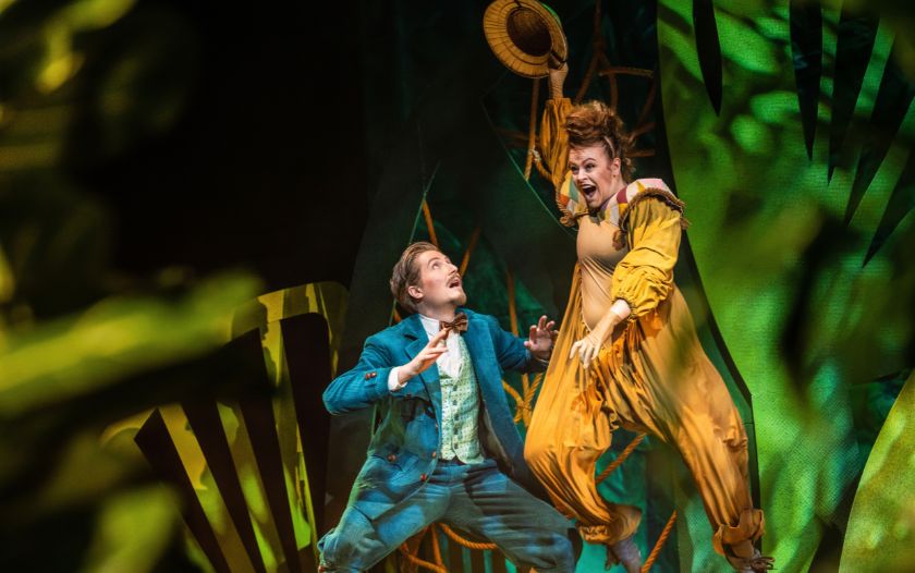 Die Affendame Tee springt erschrocken in die Luft, während ein Expeditionsteilnehmer in grünem Anzug mit aufgerissenen Augen zurückweicht.