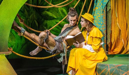 Tarzan liegt in Lianen, während er gemeinsam mit Jane ein Buch liest – Szene aus „Tarzan – das Musical“ von Theater Liberi