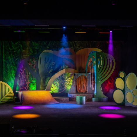 Beleuchtete, bunte Kulisse im Dschungelstil mit stilisierten Pflanzenformen.